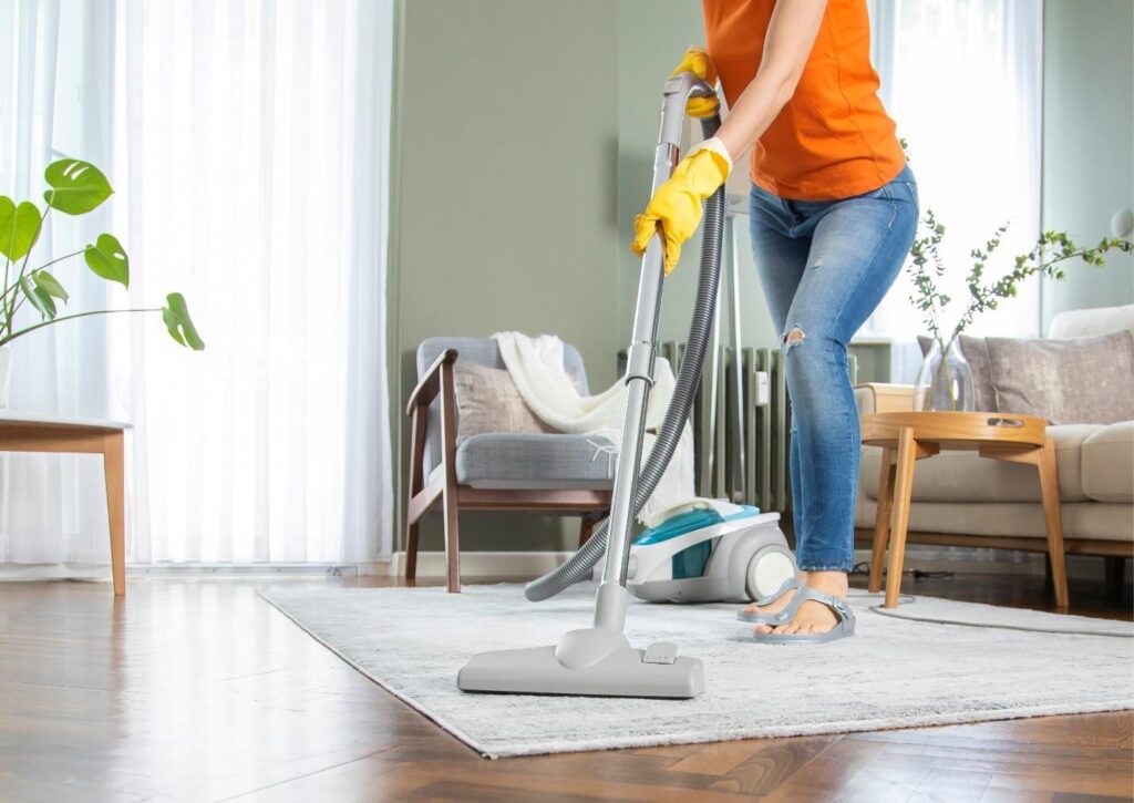 vacuuming living room carpet during regular cleaning in Reno home